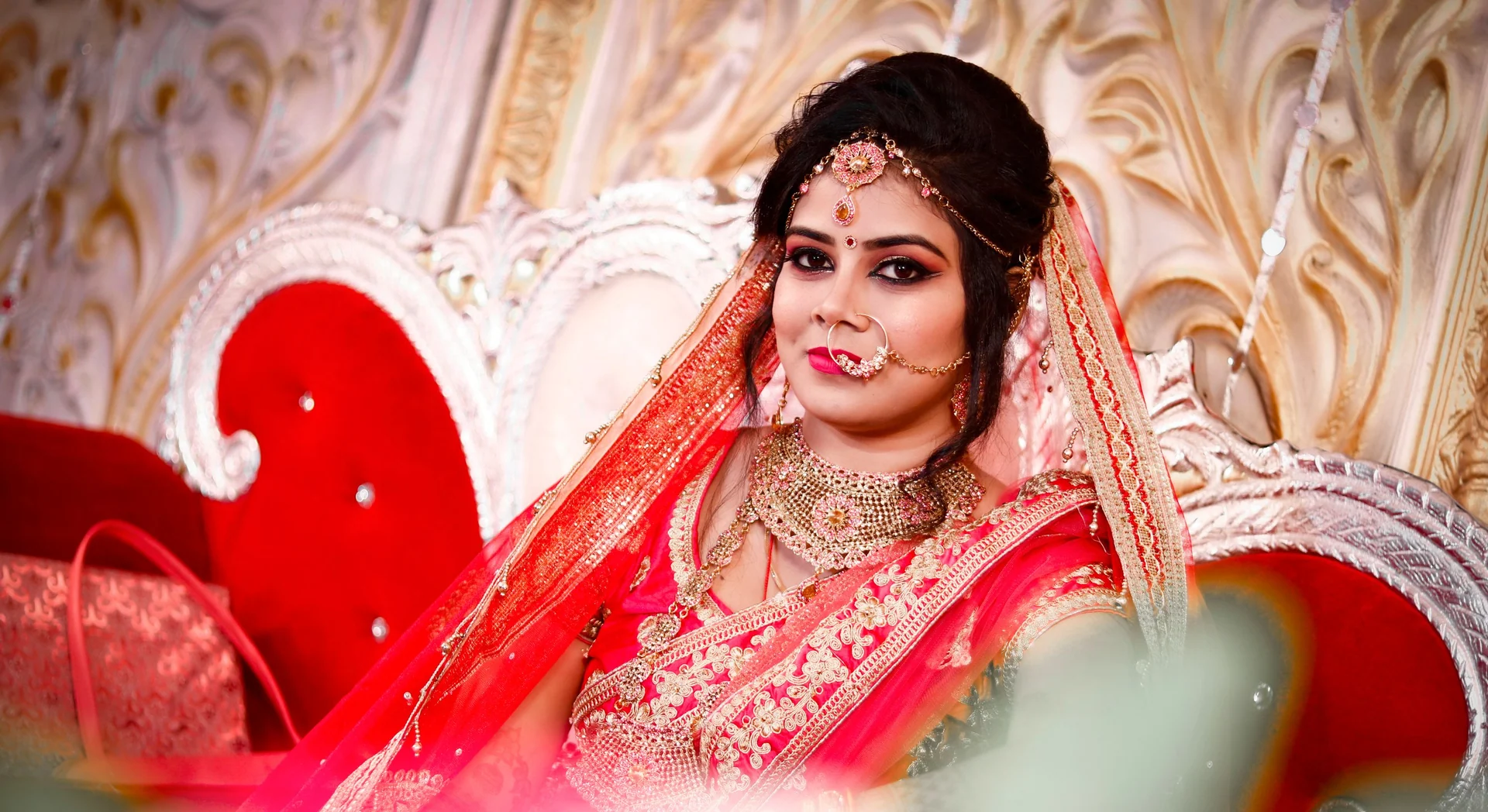 Indian bride wearing a red veil and traditional bridal jewellery